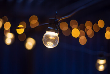 Electric lamp garlands with different size bulbs hanging in a cafe, attached to the ceiling....