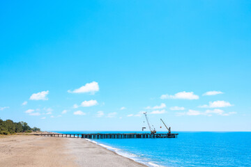 view along the seashore, the pier extending into the sea in daylight