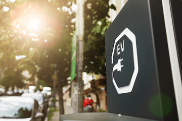 EV and plug sign on black board of electric car station at city street. Modern technology and transportation industry concept.