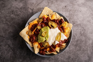 PLate of nachos with guacamole, cheese cream, jalapeños and beans