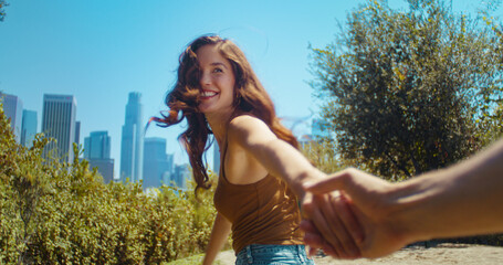 Happy woman holding boyfriends hand going at park. Asian girl leading friend.