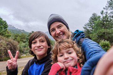 A happy family taking a selfie portrait with smartphone in the mountains in winter - Powered by Adobe