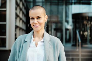 Stylish businesswoman looking at the camera and smiling while standing outdoors.