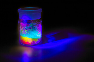 Fluorescent organic materials of red, yellow and green color for production OLED inside glass bottle in UV light.