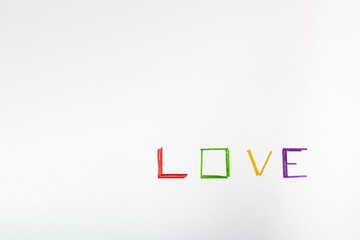 Word LOVE made of colorful sticks, red, green yellow and purple, on clear white background. Minimal Valentines concept with copy space.   Flat lay, love concept.