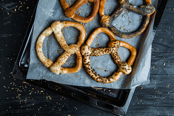 Fresh prepared homemade soft pretzels. Different types of baked bagels with seeds on a black background.