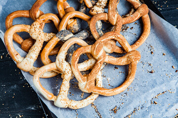Fresh prepared homemade soft pretzels. Different types of baked bagels with seeds on a black background.