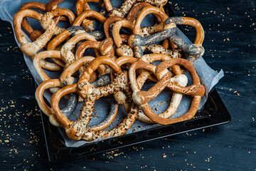 Fresh prepared homemade soft pretzels. Different types of baked bagels with seeds on a black background.