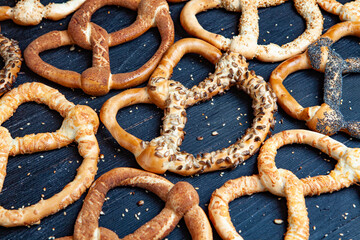 Fresh prepared homemade soft pretzels. Different types of baked bagels with seeds on a black background.