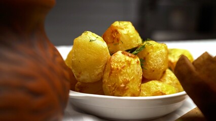 Round whole potatoes cooked in the oven. Golden fried potatoes without skins. Appetizing round fried potatoes.