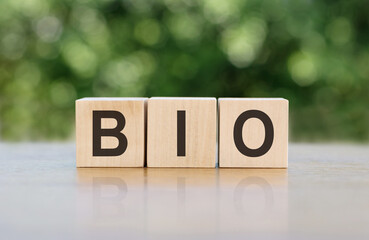 BIO text on wood block cubes on wooden table over blur green tree