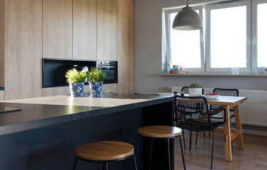 Luxurious Interior of kitchen with wooden dining table, counter made from marble and window. Dining room with space and wooden cabinet and furniture.