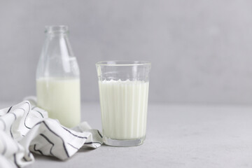 A glass of fresh milk, a bottle and textiles on a gray background. Selective focus. Copy Space