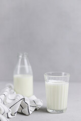 A glass of fresh milk, a bottle and textiles on a gray background. Selective focus. Vertical photo