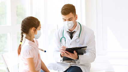 Fototapeta premium Healthcare, medicine concept: Pediatrician Doctor in wearing FFP2 face mask during Coronavirus Covid-19 infection pandemic measure the temperature of child girl