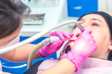 Female dentist curing a woman patient. Dental clinic and dentist appointment concept.