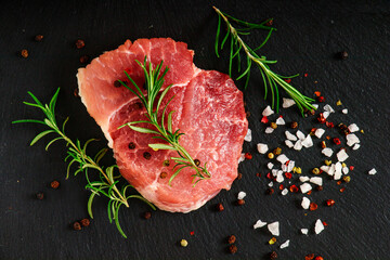 Fresh steak with herbs and spices at black background.