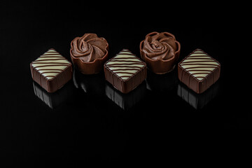 dark and white chocolate candies with cream filling on black mirroring surface