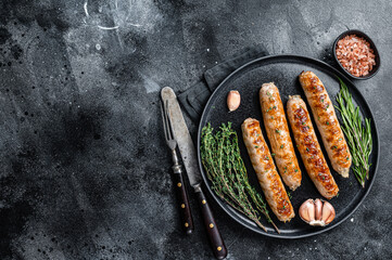 Roasted Bockwurst pork meat sausages in a plate. Black background. Top view. Copy space