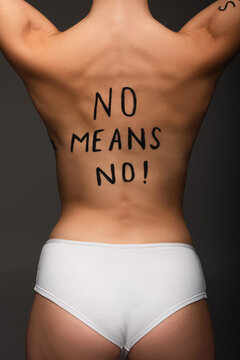 cropped view of young woman with no means no phrase written on back isolated on dark grey