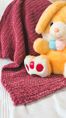 Cute, soft, rabbit in the baby's bed. Toy hare on a pink background. Children's room. Delicate background. Shades of pink. Childish transparent, blurred background.