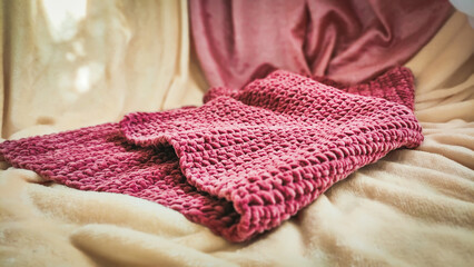 Fototapeta na wymiar Cozy knitted thick wool blanket. Corner border top view on a white wood background with copy space. Pink color.