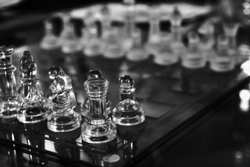 opaque and transparent glass chess pieces on the glass chessboard ready to battle