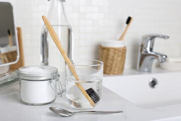 Soak a toothbrush in solution of  white vinegar, water and baking soda on the bathroom sink close up. - obrazy, fototapety, plakaty
