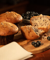 Home nade muffins with blueberries on wooden chopping board.