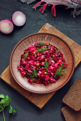 Russian vegetable salad with beetroot and other vegetables, vinaigrette in a clay plate.