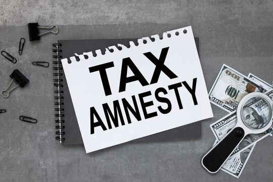 TAX AMNESTY On the desktop is a gray notebook, a white sheet of paper with text.