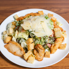 Fresh chicken salad, cheese, arugula, lettuce and croutons on a wooden table