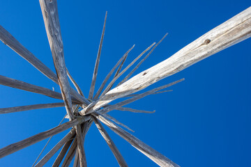 Authentic Native American teepee frame poles rising against a sharp blue winter sky
