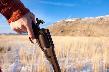 Woman's hand holding a Civil War revolver in the Wild West of a Wyoming winter, finger on the...