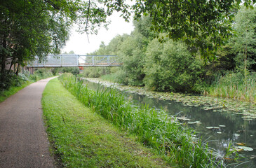 Fototapeta na wymiar View of Empty Towpath beside Reflecting Waters of Industrial Canal