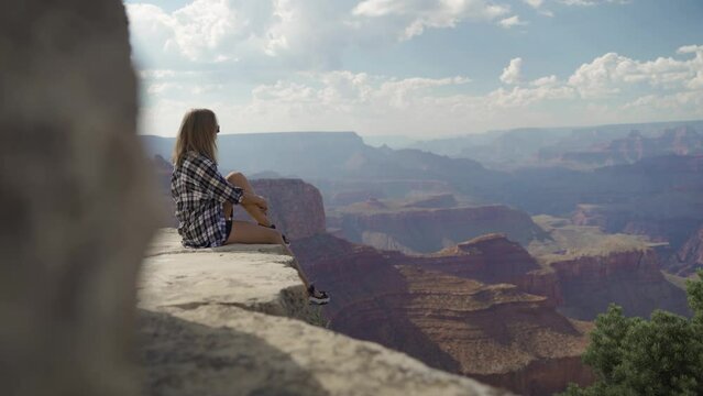A young woman looking to Horseshoe Bend and Colorado river from the edge of 1000ft canyon in Glen Canyon National Recreation Area, Arizona, USA