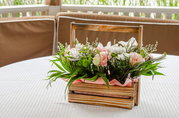 wooden basket with a bouquet of flowers on a white tablecloth.