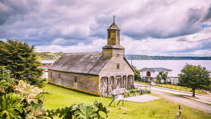 Die Holzkirche Santiago Apóstol steht auf einer grünen Wiese an der Küste von Chiloé, Chile