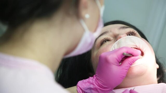 Female dentist curing a woman patient. Dental clinic and dentist appointment concept.