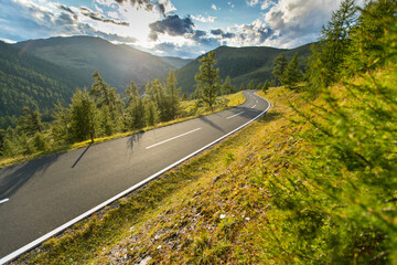 Fototapeta premium Motorbiker riding in Austrian Alps in beautiful sunset dramatic sky. Travel and freedom, outdoor activities
