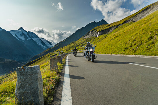 Motorbiker riding in Austrian Alps in beautiful sunset dramatic sky. Travel and freedom, outdoor activities