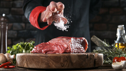 Close-up of falling salt and pepper on tasty beef steak in kitchen, freeze motion.