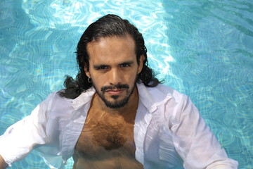 Seductive elegant ethnic man in swimming pool