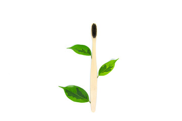 eco-friendly bamboo toothbrush in black color and green leaves lie on a white background in the form of a tree. Flat lay, top view. Copy space. Zero waste personal care product, dental care