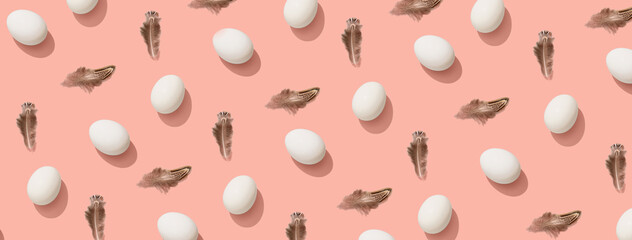 Easter eggs with feathers on pink background