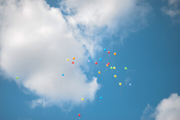 colorful balloons are flying in the blue sky with white clouds