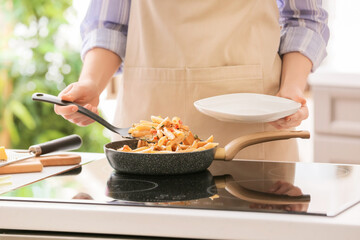 Woman putting cajun chicken pasta in plate in kitchen
