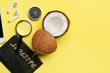 Travel items, earphones, passport and coconut on yellow background