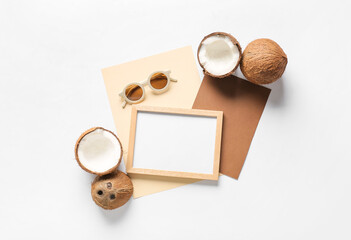 Composition with empty picture frame, cards, sunglasses and coconuts on white background