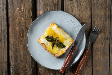 Piece of tasty hot lasagna with red wine. Small depth of field. Traditional italian lasagna. Portion. Italian food. Food on black plate. Bolognese sauce. Bechamel sauce. Still life of food